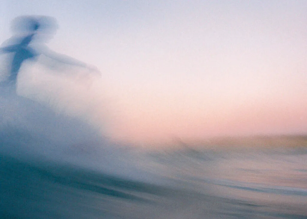Surfeur en flou de bougé sur une vague au crépuscule, tons roses et bleus, photo argentique couleur au Nikonos V - © YannB / yannb.net