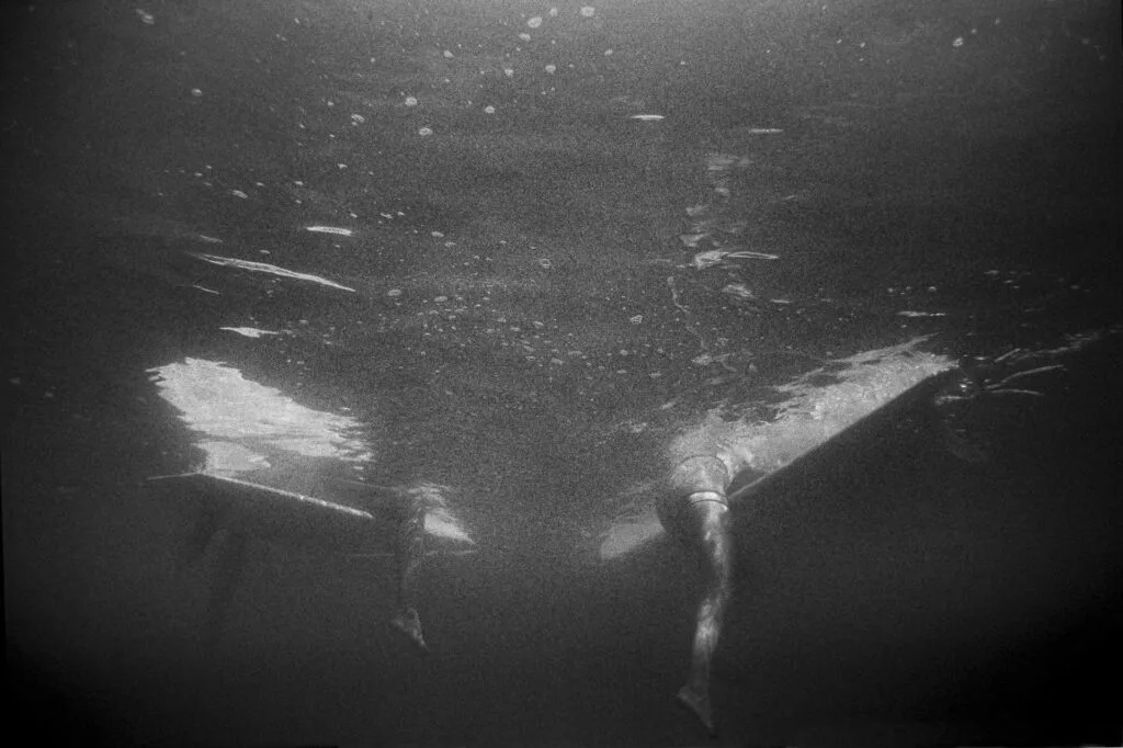 Deux surfeurs en attente vus depuis sous la surface, photo argentique noir et blanc au Nikonos V - © YannB / yannb.net