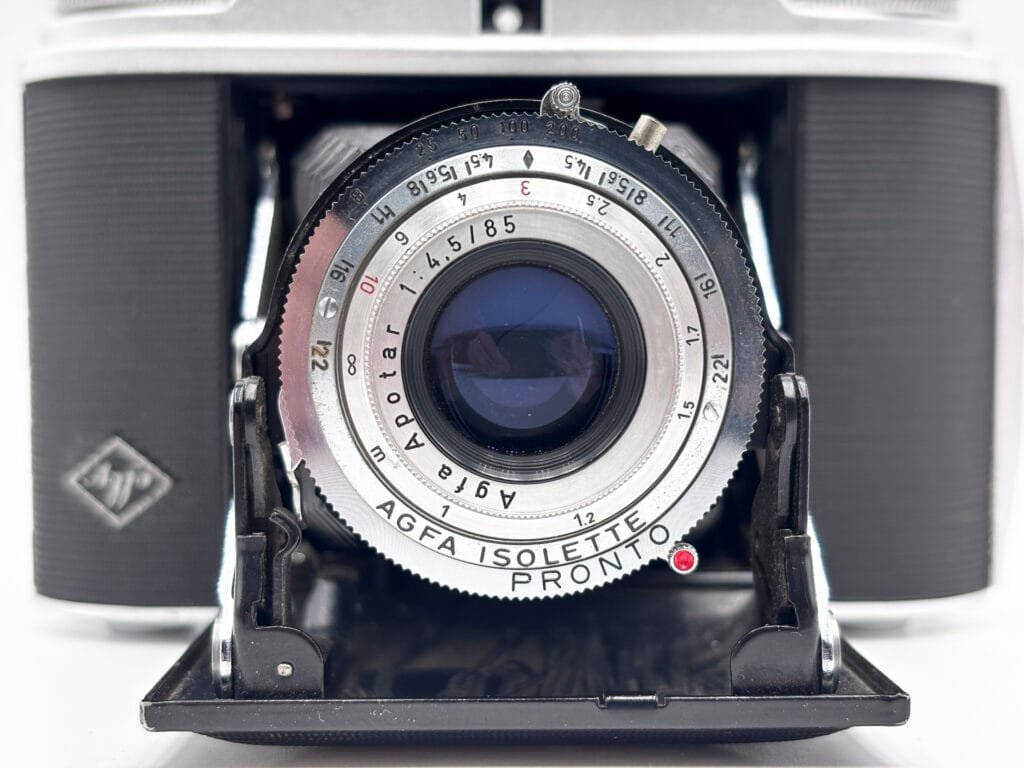 Gros plan sur l'objectif Apotar 1:4,5/85 et l'obturateur Pronto de l'Agfa Isolette II, bagues de vitesse et de distance visibles
