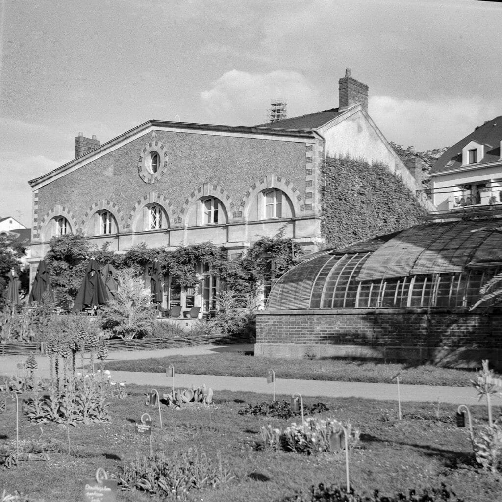 Vue d'ensemble du Jardin des Plantes de Nantes avec ses bâtiments et serres, photographiée avec l'Agfa Isolette II sur Ilford HP5