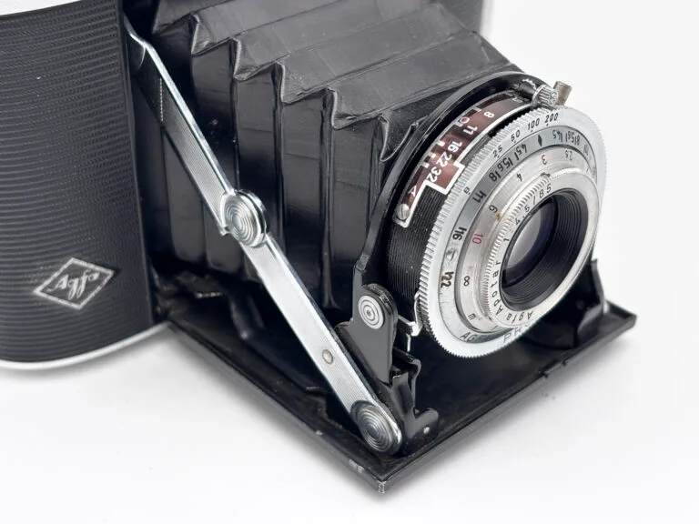 Détail de l'objectif Apotar et des bras chromés de déploiement de l'Agfa Isolette II ouvert, vue en contre-plongée