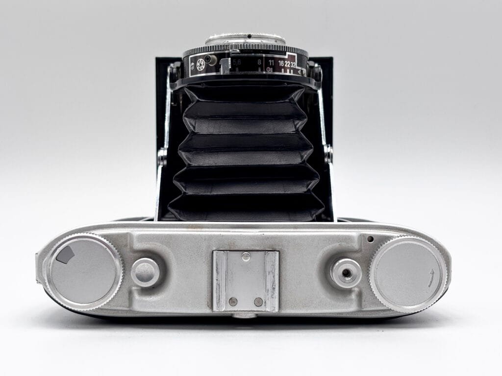 Agfa Isolette II ouvert vu de dessus, soufflet déployé, molette de transport film et déclencheur visibles sur le dessus du boîtier