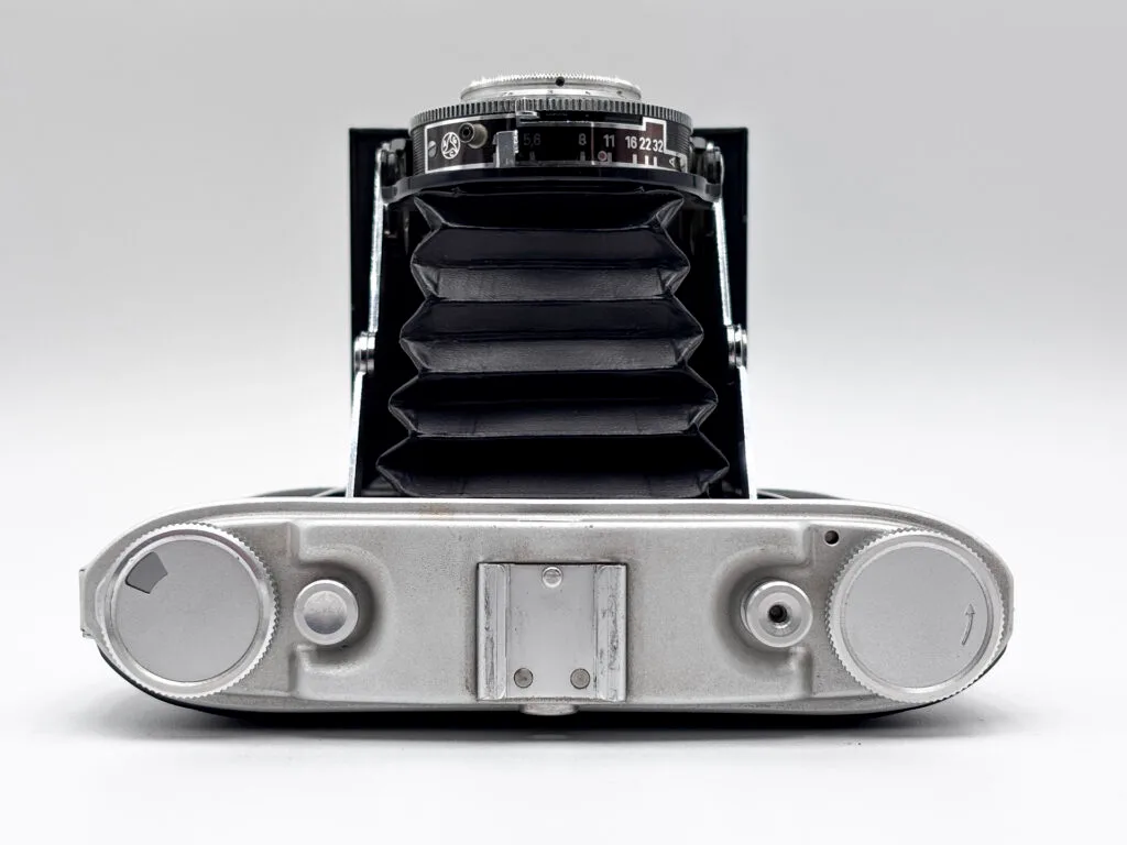 Agfa Isolette II ouvert vu de dessus, soufflet déployé, molette de transport film et déclencheur visibles sur le dessus du boîtier