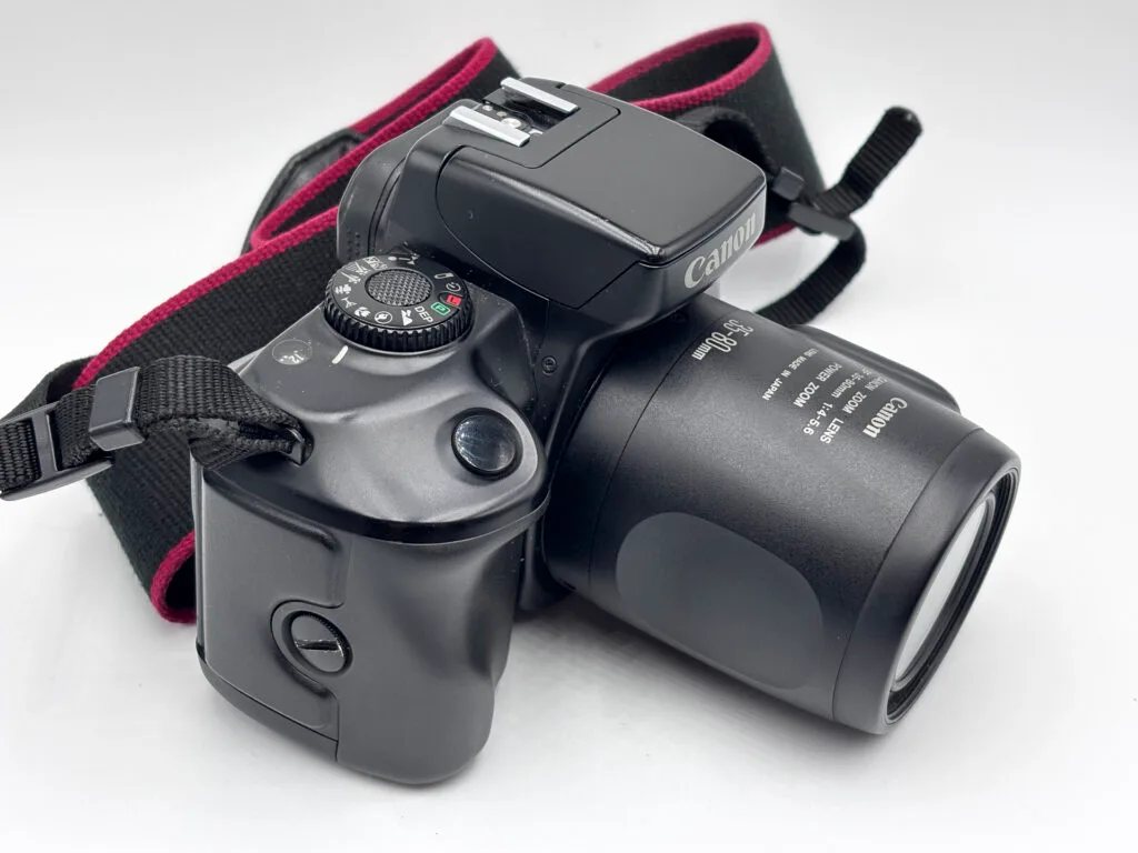 Canon EOS 700 argentique vu de trois quarts gauche, flash intégré et molette de modes visible