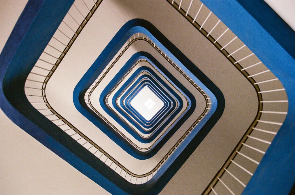 Cage d'escalier du CHU de Nantes vue en contre-plongée, rampes bleues concentriques et puits de lumière, Canon EOS 700