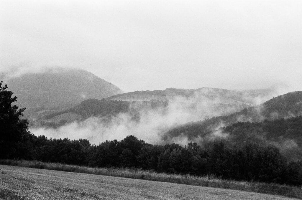 Brume matinale s'élevant sur des collines boisées près de La Mure, en Isère, photographié en noir et blanc sur pellicule Ilford HP5 avec un Nikon F6