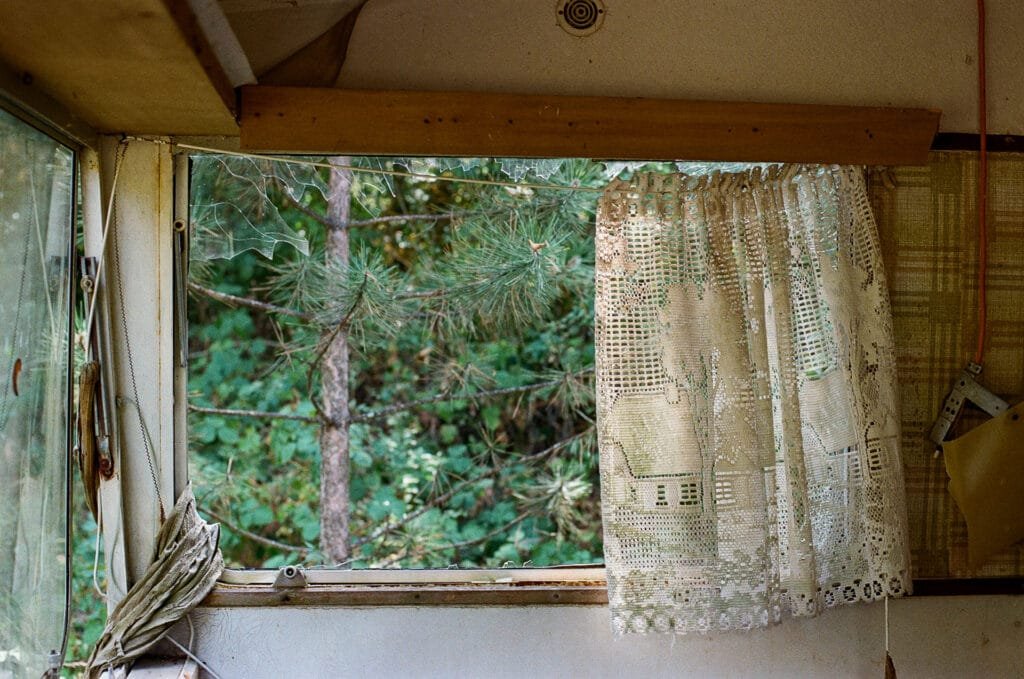 Fenêtre de caravane abandonnée avec rideau en dentelle — Nikon F6, Kodak Pro Image 100