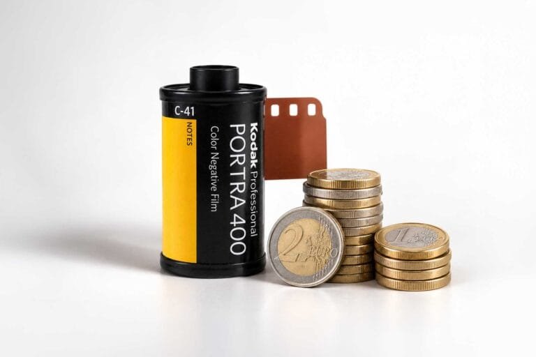 Pellicule Kodak Portra 400 à côté de piles de pièces illustrant le coût de l'argentique en 2026