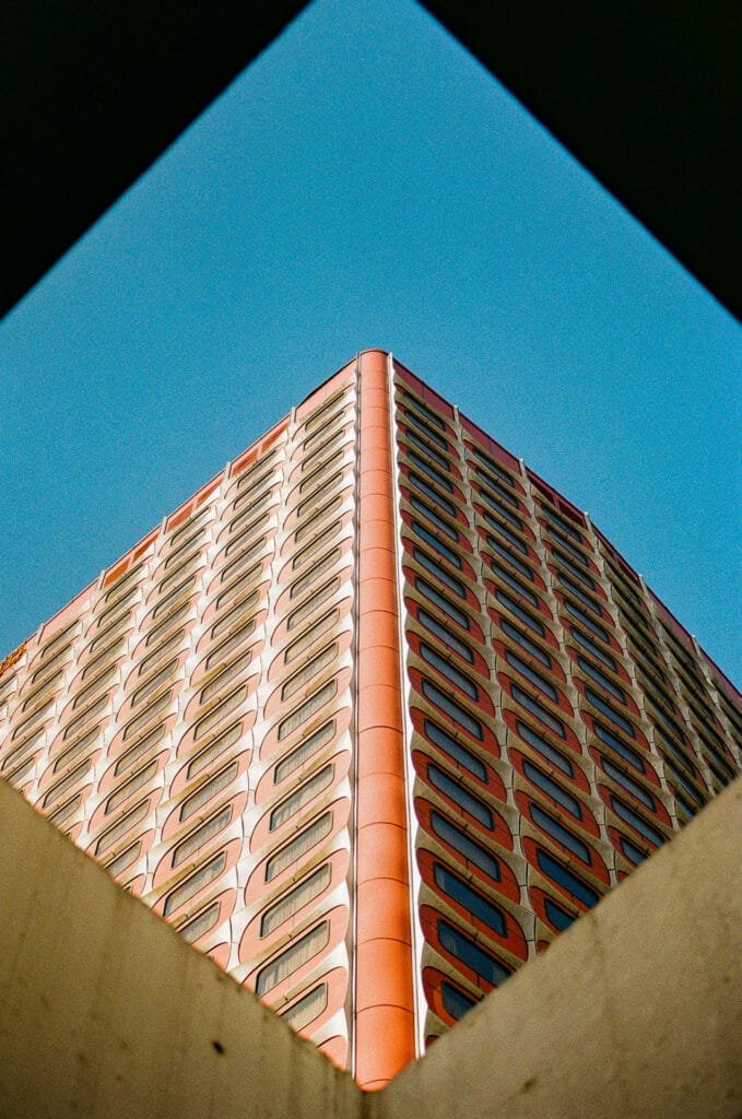 Angle de l'ancien hôtel Nikko cadré en losange entre deux murs de béton, ciel bleu, Kodak 200