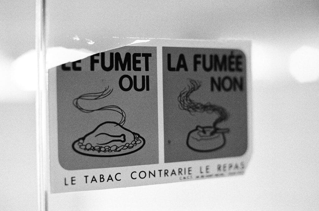 Autocollant antitabac vintage « Le fumet oui, la fumée non » sur une vitre du toit de l'Espace Niemeyer, Ilford HP5