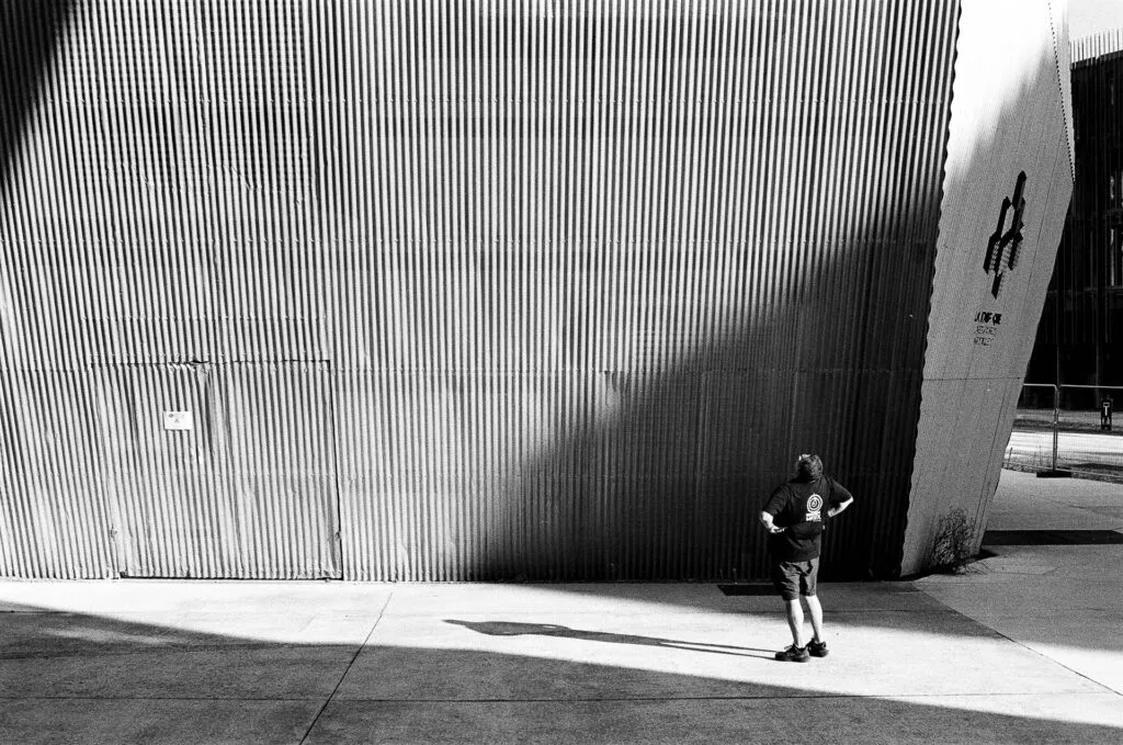 Eric Forey, formateur, de dos devant une façade en bac acier ondulé, stage photo architecture Île de Nantes