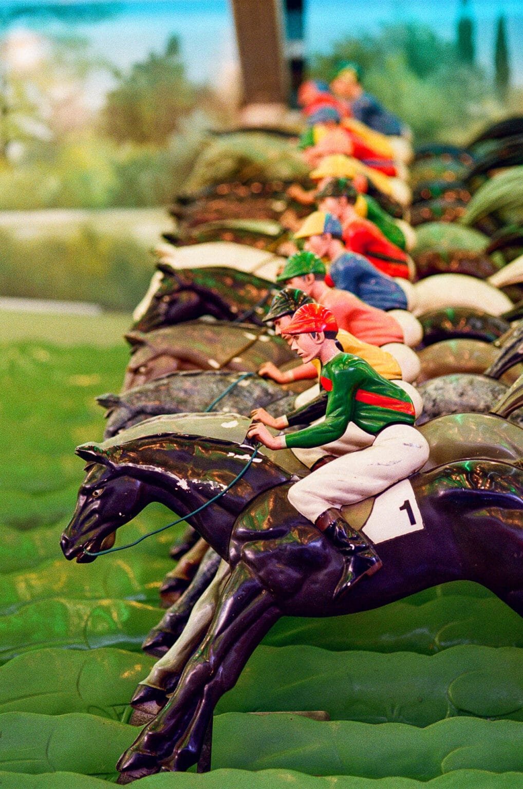 Rangée de jockeys miniatures en plastique sur leurs chevaux, jeu de course mécanique dans une fête foraine à Nantes, photographié au Nikon F6 avec un Micro-Nikkor 105mm f/2.8 AF-D sur pellicule Kodak Color 200
