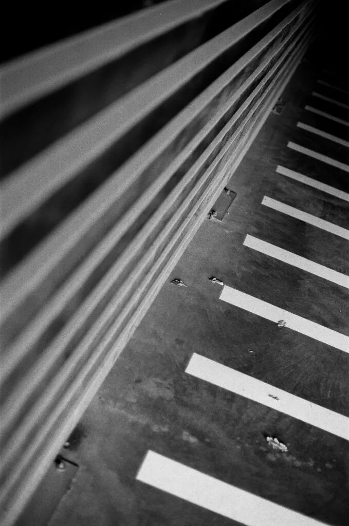 Marquage au sol d'un parking et rambarde en diagonale, rythme de lignes, argentique noir et blanc