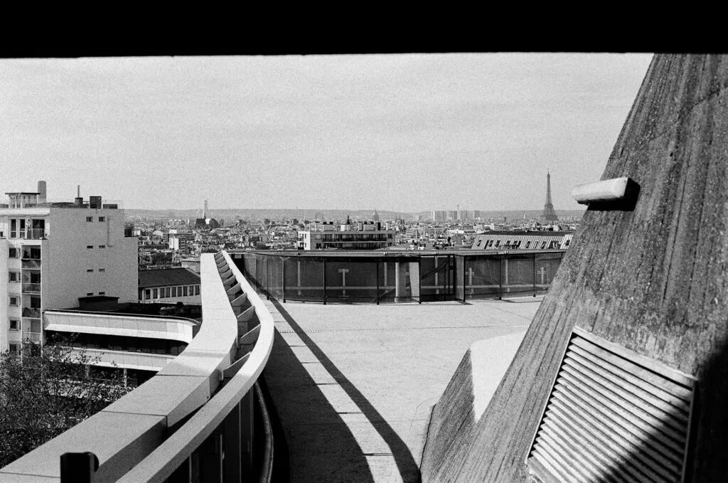 Toit-terrasse de l'Espace Niemeyer, garde-corps courbe et tour Eiffel à l'horizon, argentique noir et blanc