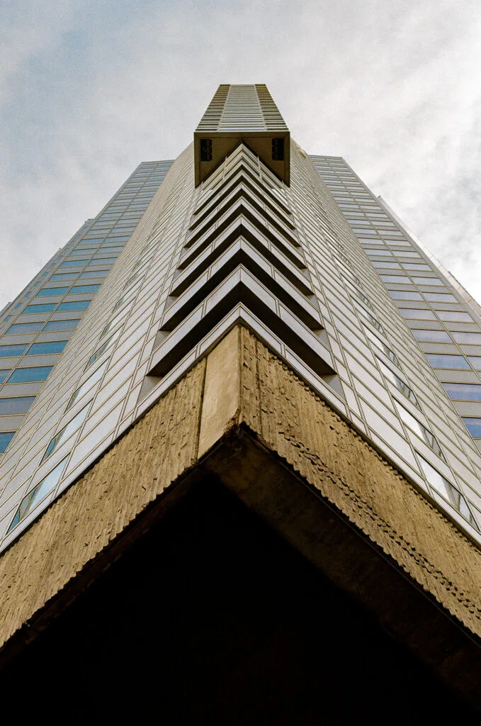 Tour du Front de Seine en contre-plongée, angles en chevrons au-dessus d'un socle en béton strié