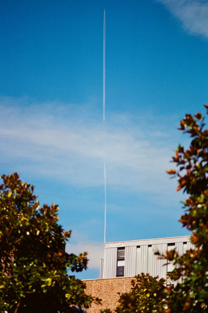 Traînée d'avion verticale comme ligne directrice, encadrée par des arbres, Île de Nantes