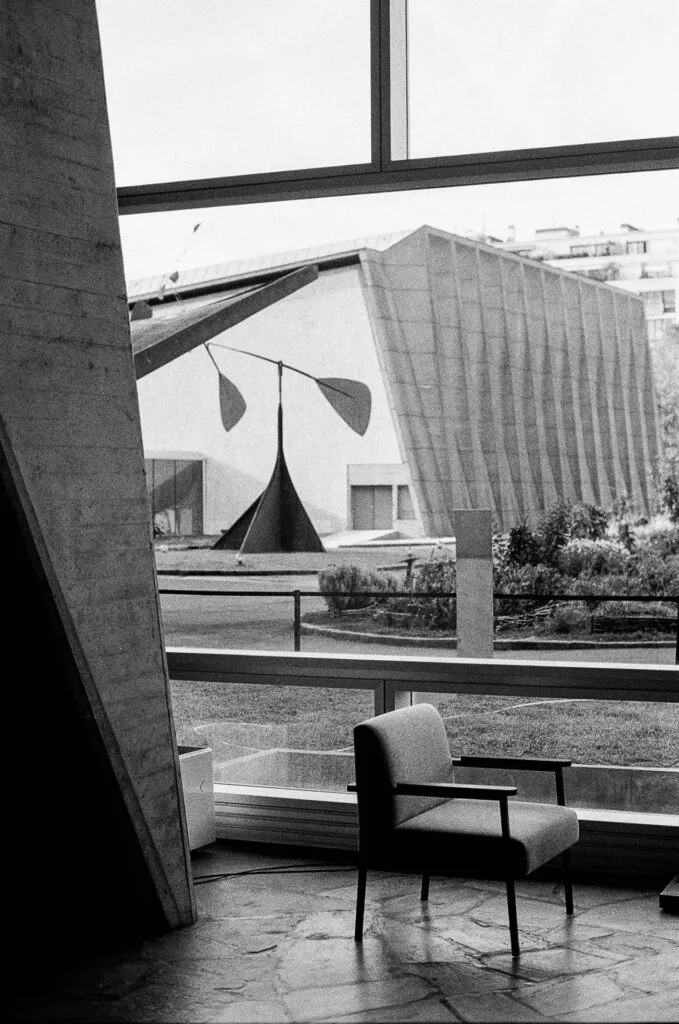 Fauteuil devant une baie vitrée du siège de l'UNESCO, Spirale de Calder et toit plissé au fond, Ilford HP5