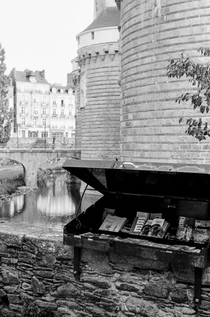 Présentoir à brochures touristiques ouvert devant les tours et les douves du château des ducs de Bretagne à Nantes