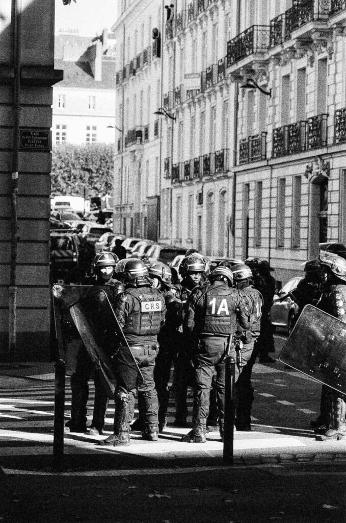 Groupe de CRS casqués avec boucliers à l'angle de la place du Port-Communeau à Nantes, façades éclairées en lumière rasante