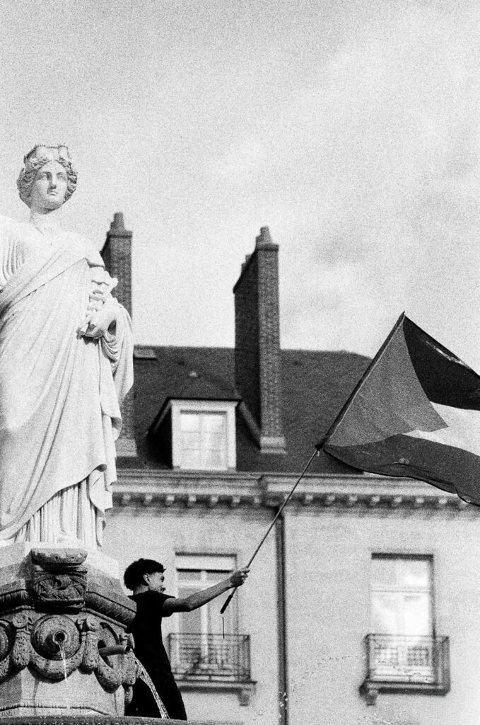 Manifestant agitant un drapeau palestinien à côté de la statue de la fontaine de la place Royale à Nantes