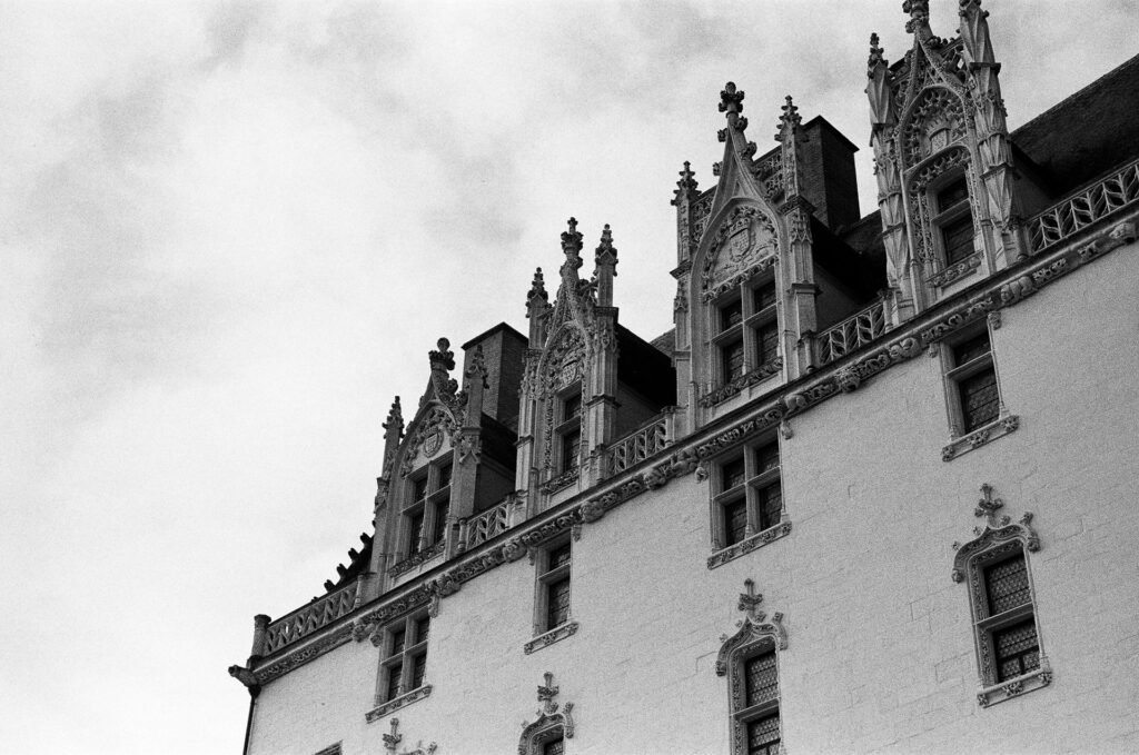 Lucarnes gothiques sculptées de la façade du château des ducs de Bretagne à Nantes, en contre-plongée sous un ciel nuageux