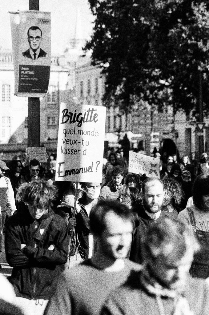 Pancarte « Brigitte, quel monde veux-tu laisser à Emmanuel ? » au-dessus du cortège à Nantes, bannière municipale en arrière-plan