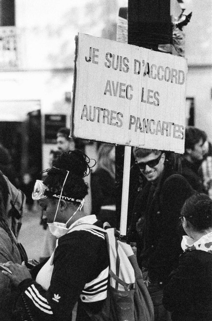 Pancarte « Je suis d'accord avec les autres pancartes » tenue sur un manche en bois au milieu des manifestants à Nantes
