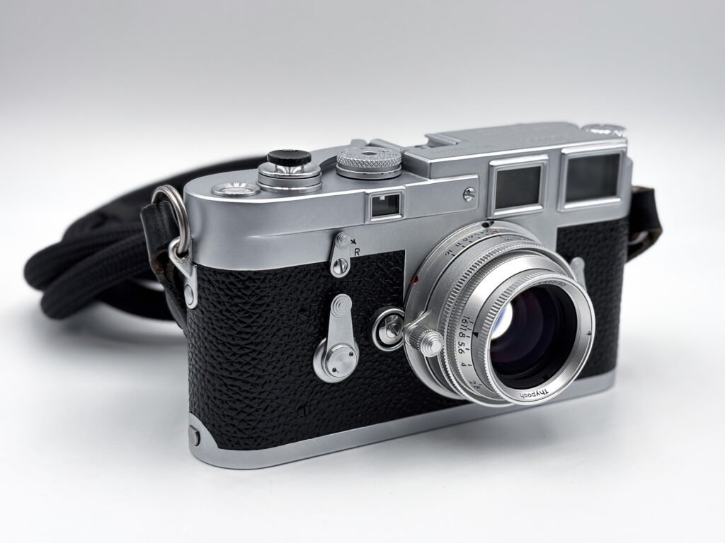 Leica M3 chromé vu de trois quarts, équipé de l’objectif Thypoch Eureka 50mm f/2 en aluminium en position rentrée, qui dépasse à peine de la monture